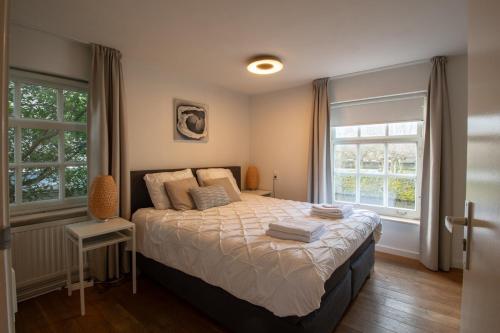 a bedroom with a bed and two windows at Unique tranquil spot with garden, centre Den Bosch in Den Bosch