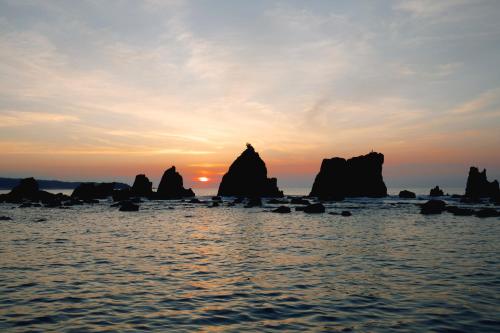 a sunset over the ocean with rocks in the water at Fairfield by Marriott Wakayama Kushimoto in Kushimoto