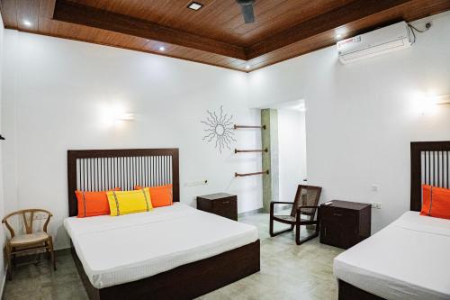 two beds with orange and yellow pillows in a room at Walker's Residency in Anuradhapura