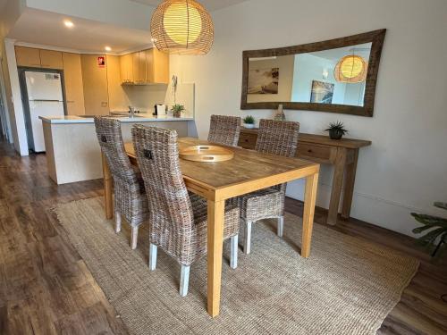 a dining room with a wooden table and chairs at Byron Quarter Apartments in Byron Bay