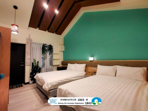 two beds in a room with a green wall at 山淺民宿 Yamasaki Old House in T'ai-pin-ts'un