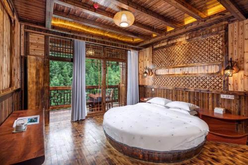 a bedroom with a large bed in a room with wooden walls at 素隐乡宿Hometown Destination红瑶吊脚楼 观景民宿 in Heping