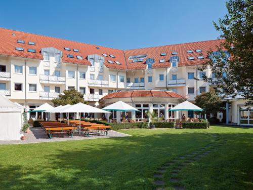 a large building with tables and umbrellas in a park at Seminaris Hotel Bad Boll in Bad Boll