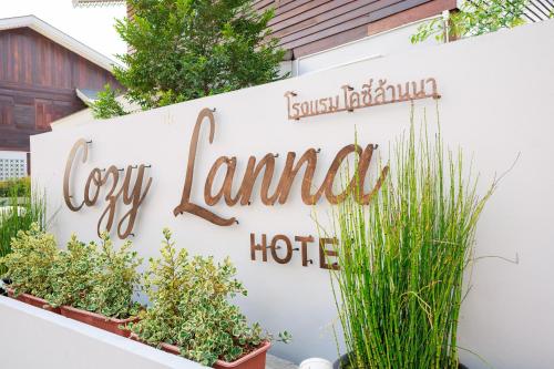 a sign for a hotel on a wall with plants at Cozy Lanna Hotel in Chiang Mai