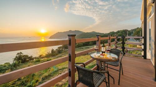 a table and chairs on a deck with a view of the ocean at Geoje Inbito Pension in Op'o