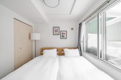 zwei Betten in einem Zimmer mit Fenster in der Unterkunft RT2 103 rk in Sapporo