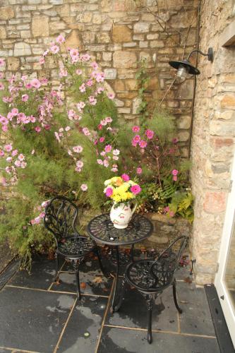 a table and chairs with a vase of flowers on it at Wassail Barn Wedmore in Wedmore