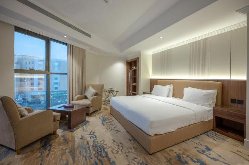 a bedroom with a bed and two chairs and a window at Quiet Dreams - Serviced Apartments King abdul Aziz Street Branch in Jeddah