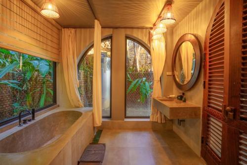 a bathroom with a tub and a sink and windows at Maida Lodge in Hòa Bình