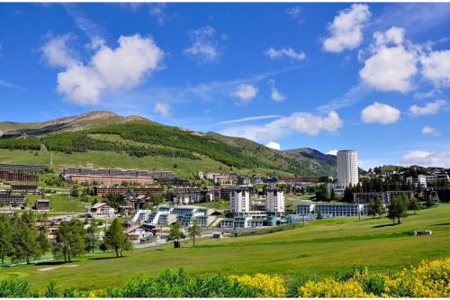 a city with a green field and mountains in the background at Appartamento Alpine Suite - Happy Rentals in Sestriere