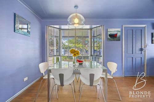 a dining room with a table and white chairs at La Maison Bleue in Ballarat