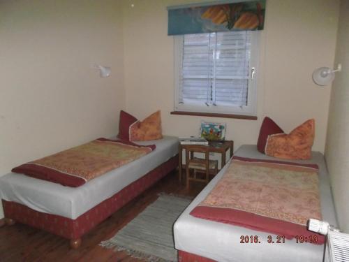 2 Betten in einem Zimmer mit einem Fenster und einem Tisch in der Unterkunft Ferienhaushälfte Lütow in Lütow