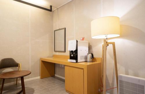 ein Zimmer mit Schreibtisch, Kaffeemaschine und Lampe in der Unterkunft Naju Holius Hotel in Naju