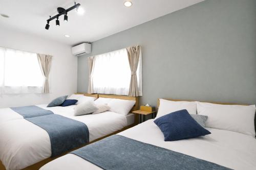 a bedroom with two beds and two windows at LAZULI Fukutsu in Fukuoka