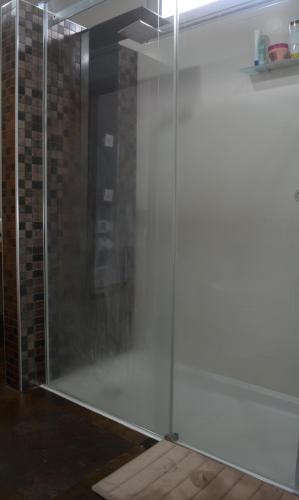 a glass shower door in a room with a brick wall at Quinta das Pedreiras in Pico da Pedra