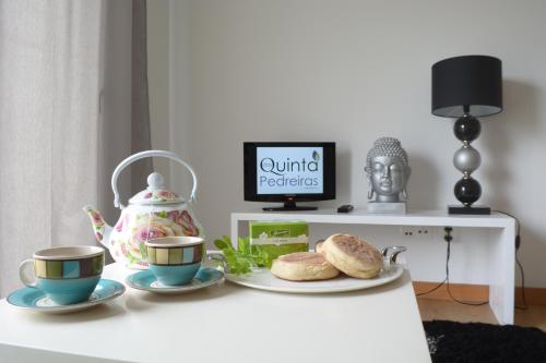 a table with two cups and a tea pot and bread at Quinta das Pedreiras in Pico da Pedra