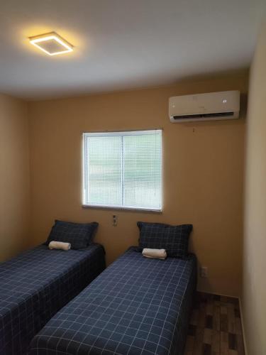 two beds in a room with a window at Haurea House in São Luís