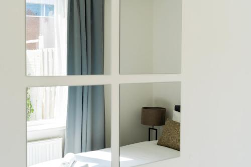 a room with a window with a bed and a lamp at Spacious Family Stay Eindhoven, Garden & Kitchen in Eindhoven