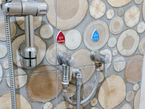 a bathroom with wooden logs on the wall at เมืองเพ็ชร์ เกสต์เฮ้าส์ in Phetchaburi