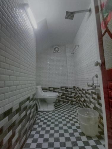 a bathroom with a toilet and a checkered floor at PERIYAR Paradize Inn,Kumily in Thekkady