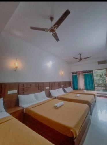 a bedroom with two beds and a ceiling fan at PERIYAR Paradize Inn,Kumily in Thekkady