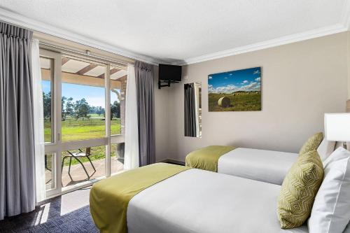 a hotel room with two beds and a large window at Quality Inn Carriage House in Wagga Wagga