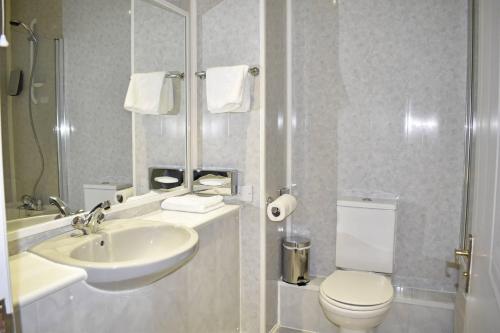 a white bathroom with a sink and a toilet at Quality Hotel Coventry in Coventry