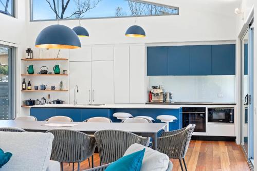 a kitchen with blue and white cabinets and a table and chairs at Architectural Beachfront Escape Yowani House in Tomakin