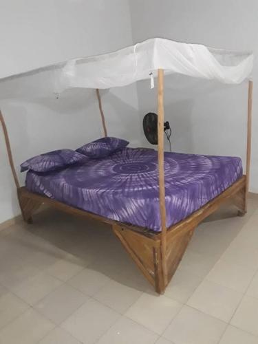 a bed with purple sheets and an umbrella at Chambre simple à louer in Fatick