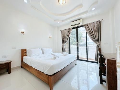 a bedroom with a bed and a large window at เมืองเพ็ชร์ เกสต์เฮ้าส์ in Phetchaburi