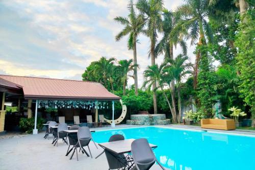 a swimming pool with tables and chairs and palm trees at Alta Cebu Resort Mactan powered by Cocotel in Mactan