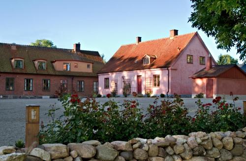 une maison rose avec une clôture en pierre devant elle dans l'établissement Brösarps Gästgifveri & SPA, à Brösarp