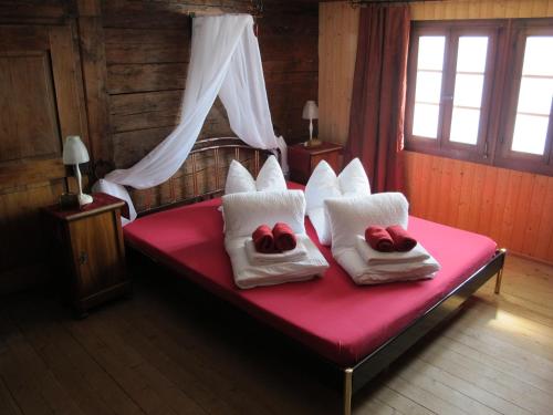 ein Schlafzimmer mit einem roten Bett mit weißen Kissen in der Unterkunft Hostel Rotschuo Jugend- und Familienferien in Gersau