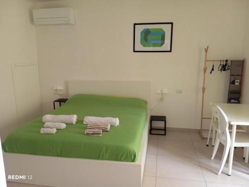 a bedroom with a green bed with towels on it at Casa vacanze TRINISULA Sicily home in Scicli
