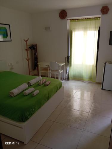 a bedroom with a bed with green sheets and slippers on it at Casa vacanze TRINISULA Sicily home in Scicli