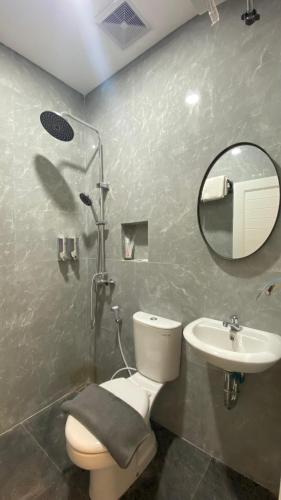 a bathroom with a toilet and a sink and a mirror at Koa Living Semarang in Kalibanteng-kidul