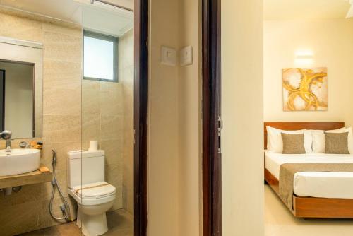 a bathroom with a toilet a sink and a bed at Marine Suites in Colombo