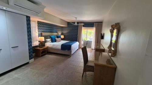a bedroom with a bed and a desk and a mirror at Luxury 3BR Direct Beach Access & Pool in Cap Malheureux