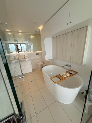 a white bathroom with a tub and a toilet at Vitamin Sea - Gold Coast luxury on the lagoon in Gold Coast