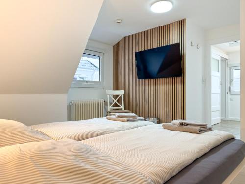 two beds in a room with a tv on a wall at Haus Meereswoge, Duhnen in Cuxhaven