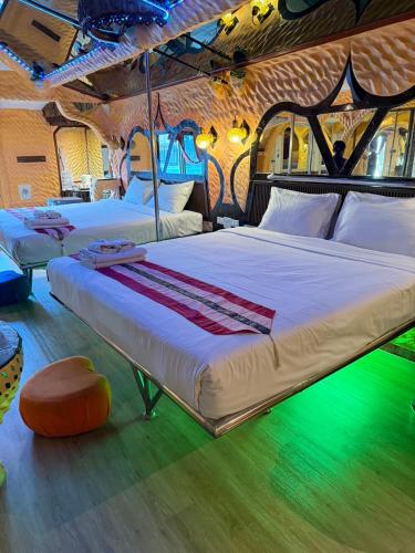 two beds in a room with green lighting at PENTHOUSE PATTAYA in Pattaya