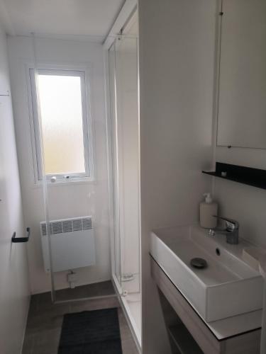 Un baño blanco con lavabo y ventana. en Ohana, en Puget-sur-Argens