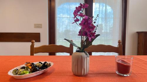 a vase with purple flowers and a bowl of food on a table at La Casa di Ekeko in Vivaro