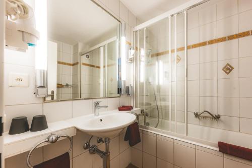 a bathroom with a sink and a shower at Hotel Alfa Superieur - Leukerbad-Therme in Leukerbad