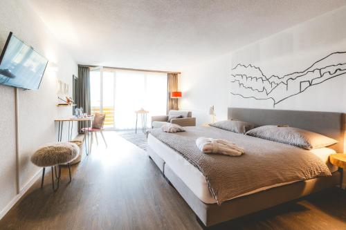 a bedroom with a large bed and a tv at Hotel Alfa Superieur - Leukerbad-Therme in Leukerbad