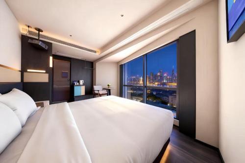 a bedroom with a large white bed and a large window at Skyline Grand International Hotel - Prime Tianhe City Center Walkable Subway Top Pick for Canton Fair Stunning High Floor Panoramic City View Luxury Guest Rooms in Guangzhou