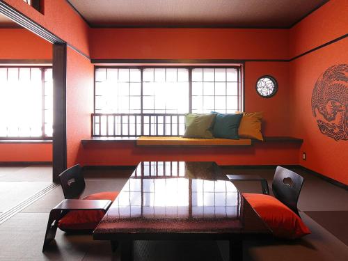 a room with a bed and a table and windows at Goyokan in Izu