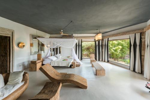 a living room with a bed and benches and windows at The Majlis Resort in Lamu