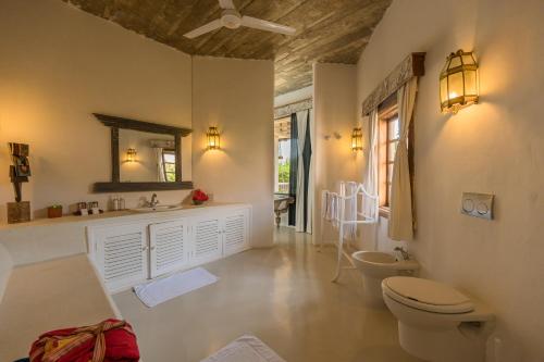 a bathroom with a toilet and a sink and a mirror at The Majlis Resort in Lamu