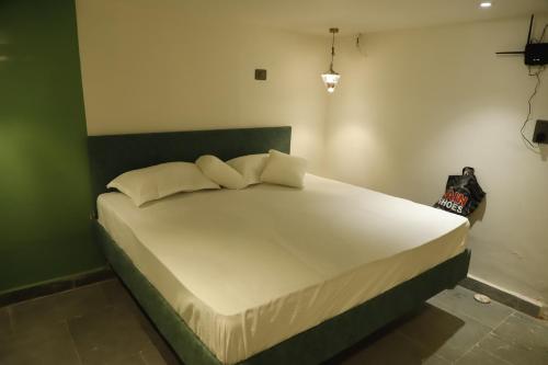 a bedroom with a large white bed with a green headboard at Grenelle-Indirapuram in Ghaziabad